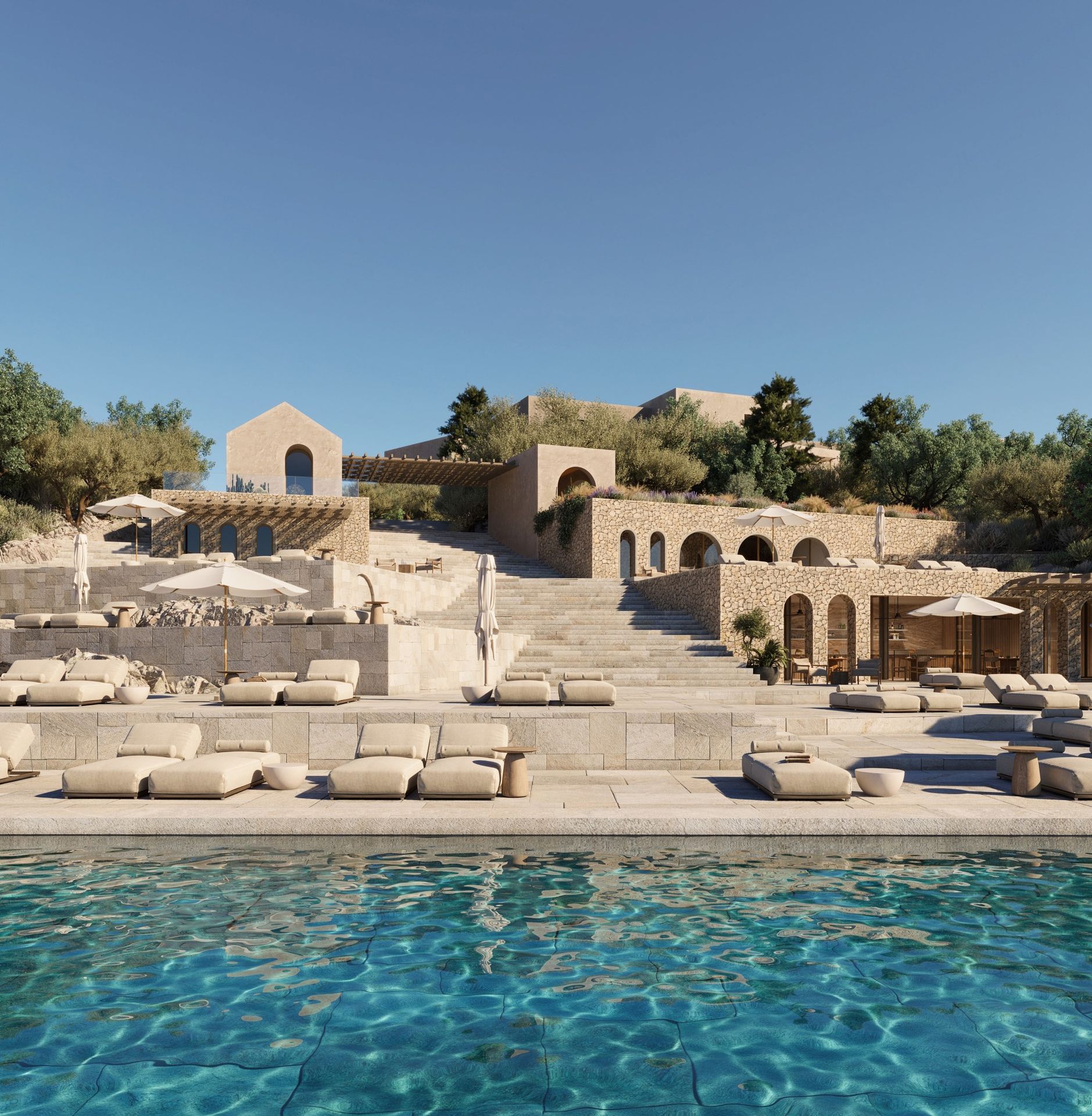 Village beach club pool with loungers on stepped stone terraces below an arcade